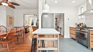 Een moderne keuken met een groot schiereiland, roestvrijstalen apparatuur en een eethoek met houten meubels.