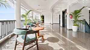 A hotel corridor with seating areas, ceiling fans, potted plants, and a fire extinguisher. - Verano Hotel & Spa  (Arpora)