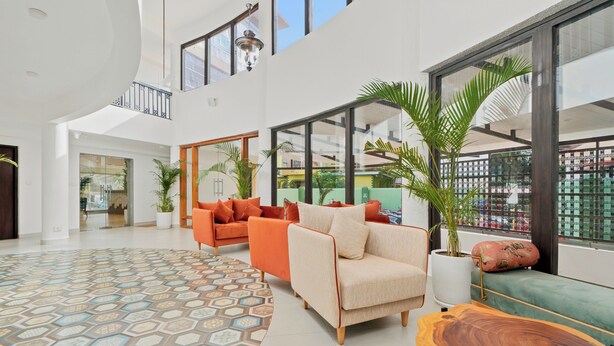 A spacious indoor area with a high ceiling, large windows, and a mix of seating arrangements including sofas and a bench. - Verano Hotel & Spa  (Arpora)