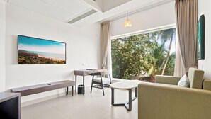 A modern living room with a large window, a flat-screen TV, a sofa, a dining table, and a bench. - Verano Hotel & Spa  (Arpora)