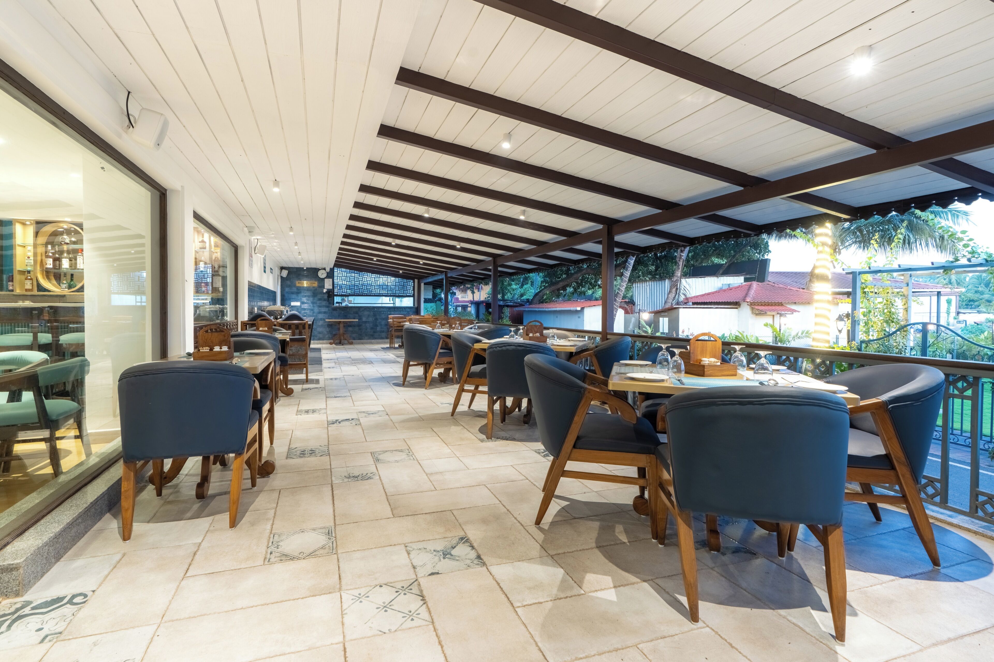 Restaurante com mesas e cadeiras de madeira, áreas externas e vista para a região ao redor.