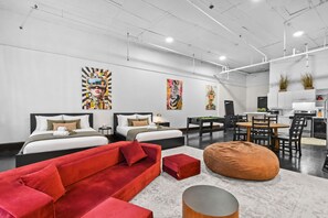 A modern hotel room with two beds, a red sofa, a dining table, and a kitchen area. - Cozy open concept Loft in the Heart of Old Port (Montréal)