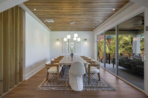 A dining area with a wooden ceiling, a long table, and chairs. - Big Kahuna Steps to Beach w/ Waterslide Pool & Spa (Sarasota)