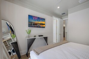 A bedroom with a bed, a painting, a desk, and a mirror. - Big Kahuna Steps to Beach w/ Waterslide Pool & Spa (Sarasota)