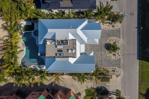 A residential property with a swimming pool, a covered patio, and a well-maintained lawn. - Big Kahuna Steps to Beach w/ Waterslide Pool & Spa (Sarasota)