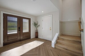 A spacious entryway with a wooden floor, a white door, and a staircase leading to an upper level. - Big Kahuna Steps to Beach w/ Waterslide Pool & Spa (Sarasota)