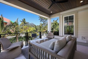 A balcony with a sofa and chairs, a sign prohibiting jumping, and a view of palm trees and buildings. - Big Kahuna Steps to Beach w/ Waterslide Pool & Spa (Sarasota)