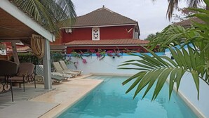 Ein Schwimmbecken mit Liegestühlen und einer überdachten Sitzgelegenheit.