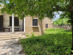A building with a staircase leading to a door, a window with shutters, and a tree providing shade. - Quiet, secure villa with private pool and private beach close to leisure activities (Saly)
