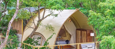 A tented accommodation with a wooden deck, a table, and a bench.