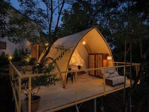 A tent with a wooden deck and a bed, surrounded by trees. - Esencia de Miel Villas & Boutique Safari (La Cruz)