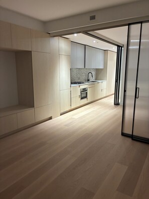 Una cucina moderna con mobili chiari in legno, un lavello in acciaio inossidabile e un forno integrato.
