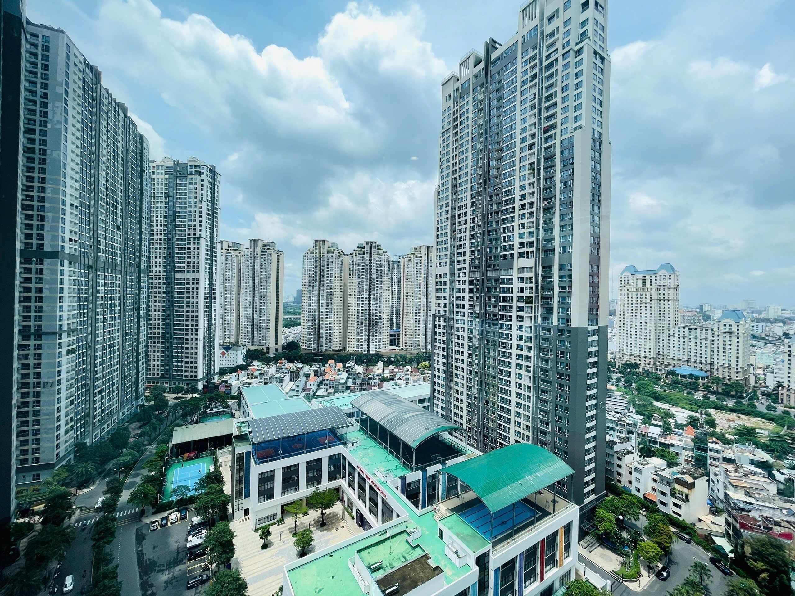 A high-rise residential building complex with multiple apartment buildings, a central courtyard with a swimming pool, and surrounding greenery.