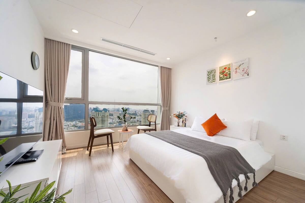 A modern hotel room with a large bed, a desk, and a view of the city.