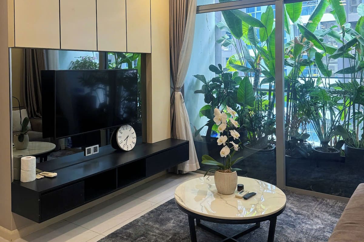 A modern living room with a flat-screen TV, a clock, and a coffee table.