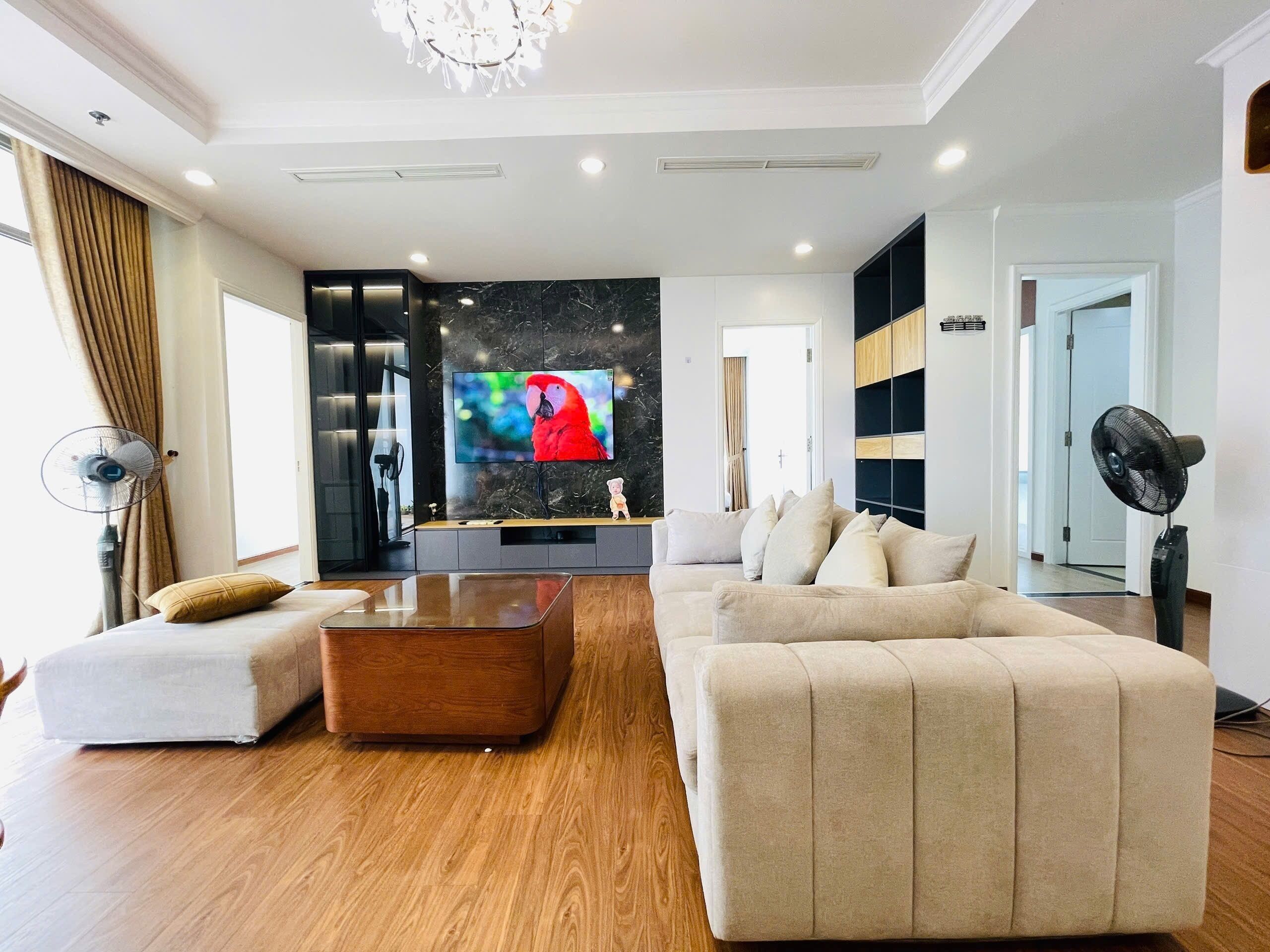 A modern living room with a large flat-screen TV, a wooden coffee table, and two sofas.
