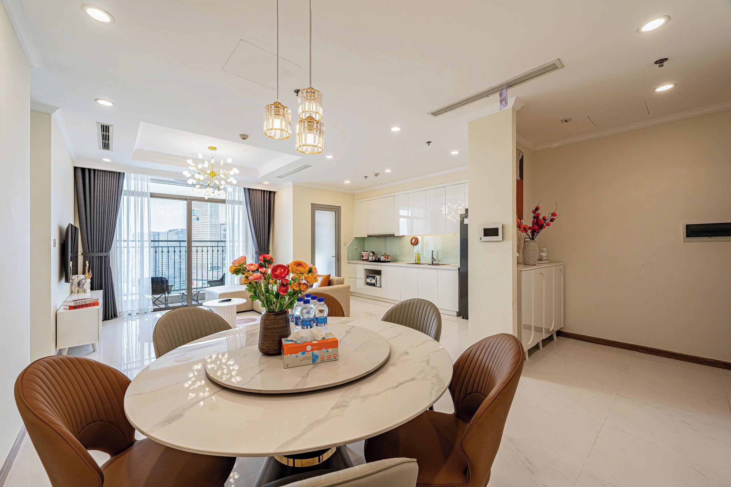 A modern dining area with a round table, chairs, and a vase of flowers.