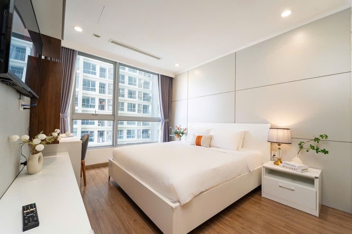 A modern hotel room with a large bed, a desk, and a nightstand.