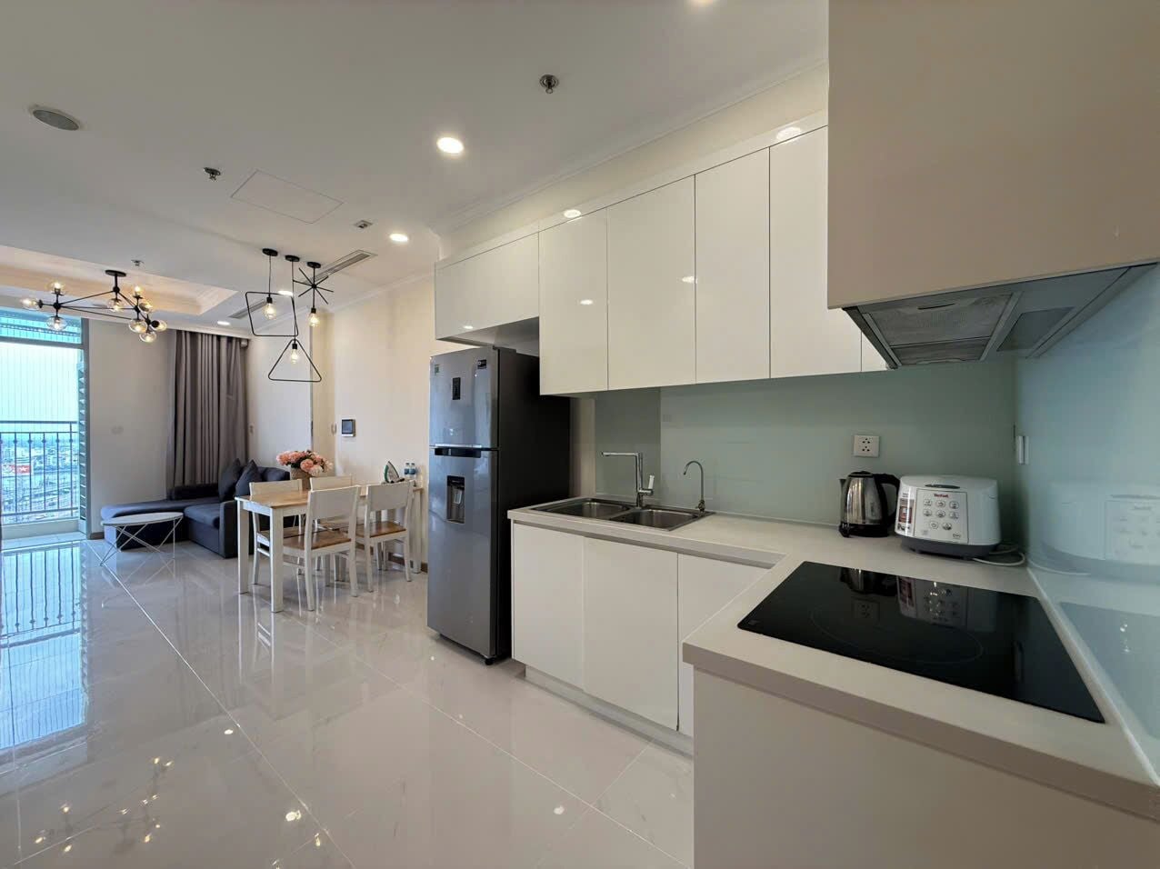 Una cocina moderna con gabinetes blancos, una estufa negra y un comedor con mesa y sillas.