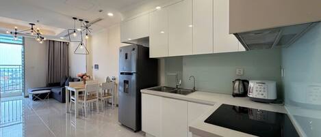 Una cocina moderna con gabinetes blancos, una estufa negra y un comedor con mesa y sillas.