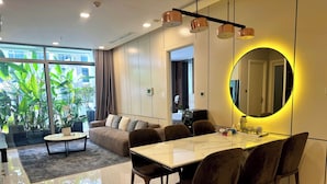 A modern living room with a sofa, coffee table, and dining area with chairs. - Saigon Stay at Vinhomes Central Park (Ho Chi Minh City)