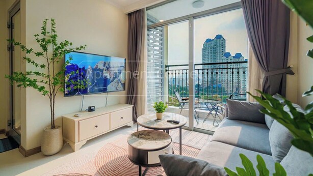 A modern living room with a large TV, a sofa, a coffee table, and a balcony with a view of a cityscape. - Saigon Stay at Vinhomes Central Park (Ho Chi Minh City)