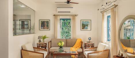 A living room with a sofa, two armchairs, a coffee table, and a large mirror.