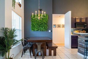 Une cuisine moderne avec des meubles de couleur sombre, un four à micro-ondes encastré et un îlot central doté de tabourets de bar.