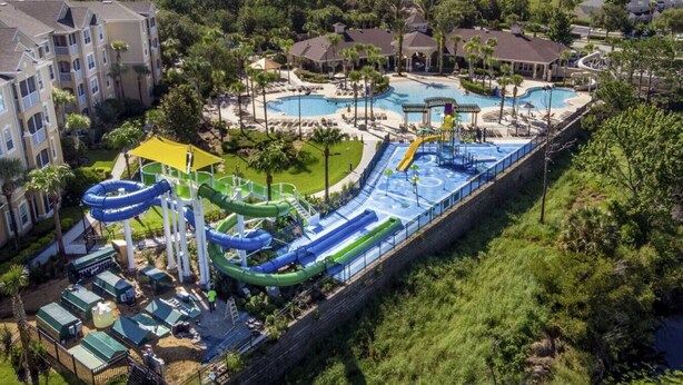 Parque acuático con varias piscinas y toboganes, rodeado de edificios residenciales.