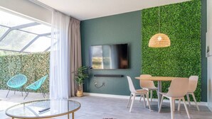Una sala de estar moderna con televisor, pared verde y zona de estar.