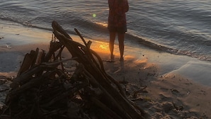 Una persona pesca al tramonto in riva all'acqua.