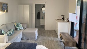 Una camera da letto moderna con un letto, una poltrona, una panca in legno e una scrivania con un lavandino.