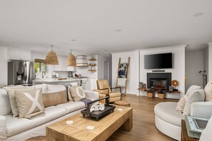 A modern living room with a sofa, coffee table, and a fireplace. - Magnificent Oceanview Retreat w/ Hot Tub, Wraparound Deck & Luxe Primary Suite, Foosball, EV Charger (Tillamook)