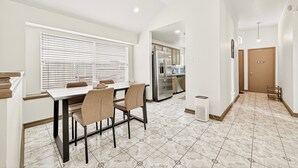 A modern kitchen with a dining area, featuring a large window, a refrigerator, and a patterned floor. - Retreat with this charming home in Asian Town Houston. (Houston)