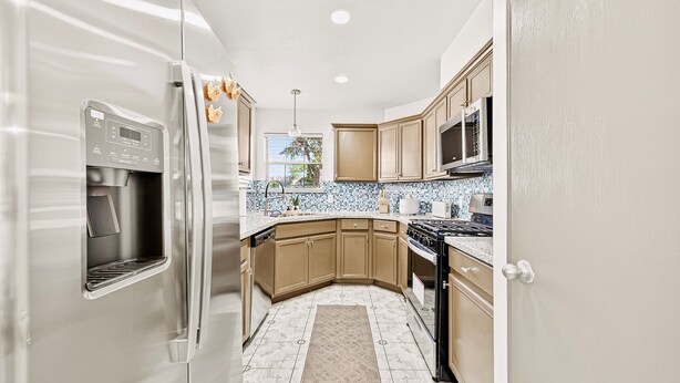 A modern kitchen with stainless steel appliances, wooden cabinets, and a tiled backsplash. - Retreat with this charming home in Asian Town Houston. (Houston)