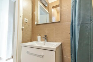 A bathroom with a white sink, a mirror, and a shower head. - Affordable Stay Near Wiener Stadthalle (Vienna)