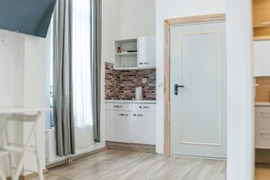 Eine kleine Küche mit weißen Schränken, einer Ziegelrückwand und Holzboden.