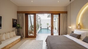 A modern bedroom with a large bed, a sofa, a view of an outdoor swimming pool, and a staircase leading to an upper level. - Modern Villa 2BR Casa Azuca by OriVista (Canggu)