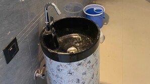 Une salle de bain avec un lavabo, des toilettes et un seau bleu.