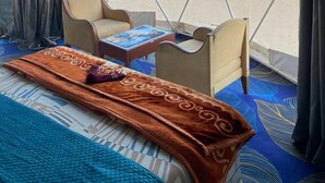Une pièce aménagée avec une tente, comprenant un lit, deux chaises, une table et donnant sur un espace extérieur.