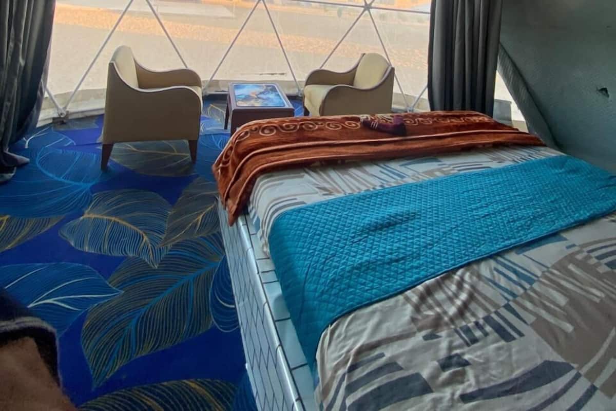 A cozy interior with a bed, two chairs, and a table.