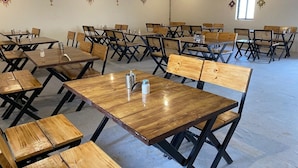 Une pièce spacieuse, dotée de nombreuses tables et chaises en bois, disposées en rangées.
