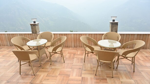 Una terraza con mobiliario de mimbre y vistas a las montañas.