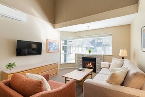 Ein Wohnzimmer mit Kamin, Fernseher und einer Couch.