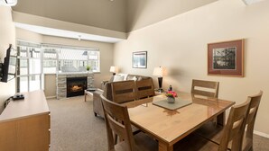 Ein Wohnzimmer mit Kamin, Esstisch mit Stühlen, einer Couch und einem Fernseher.