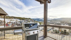 En grill på en balkong med utsikt över en snötäckt bergsby.