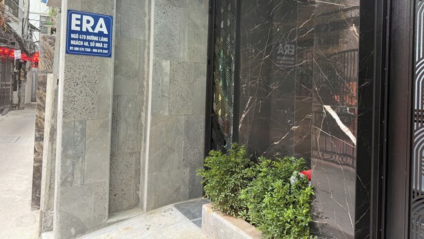 Fachada de edificio con letrero del hotel ERA, un pilar de hormigón y una pared de mármol negro con diseño geométrico.