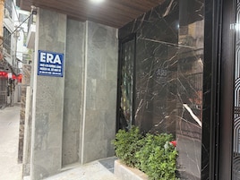 Fachada de edifício com placa do hotel ERA, um pilar de concreto e uma parede de mármore preto com design geométrico.