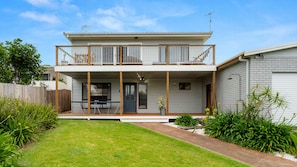 A two-story house with a balcony, a covered porch, and a small garden area. - Souira Beach House is pet friendly (Manyana)