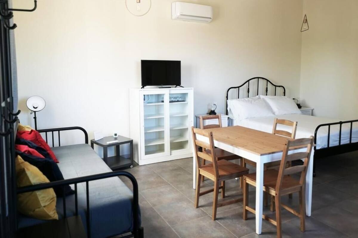 Een kamer met een bed, een bureau, een stoel, een televisie en een kledingkast.